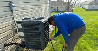 BreezeTech Heating and Cooling technician servicing a residential air conditioner in a backyard