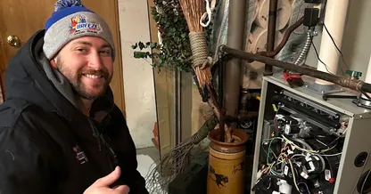 BreezeTech Heating and Cooling technician giving a thumbs up while repairing a furnace