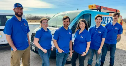 The BreezeTech Heating and Cooling crew in matching blue polos in front of their service vans
