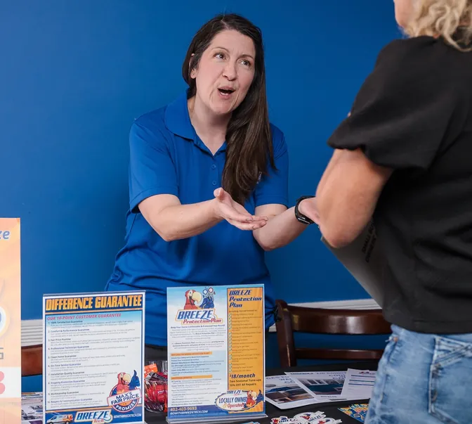 BreezeTech Heating and Cooling team member talking with a neighbor at a community event booth