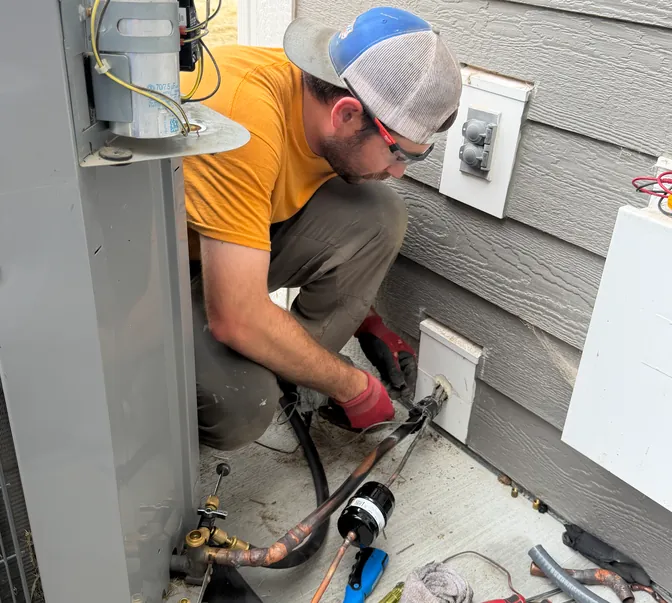 BreezeTech Heating and Cooling technician connecting refrigerant lines at an outdoor unit