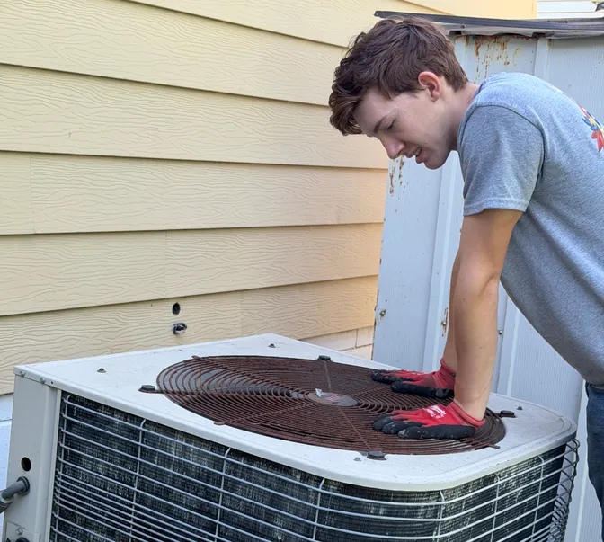 BreezeTech Heating and Cooling technician working on an old air conditioner before replacement