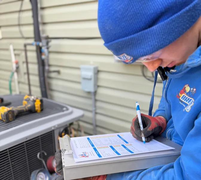 BreezeTech Heating and Cooling technician filling out a maintenance checklist beside an AC unit