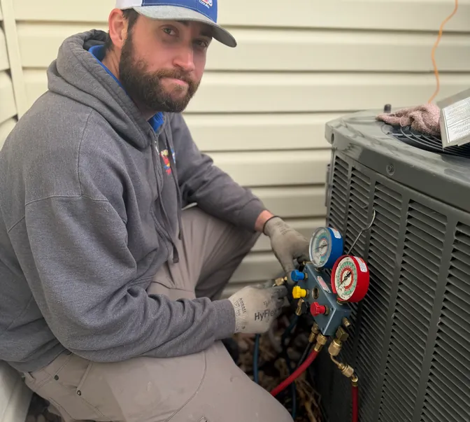BreezeTech Heating and Cooling technician checking refrigerant pressures on a heat pump