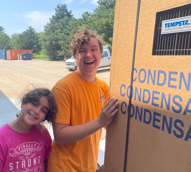 BreezeTech Heating and Cooling kids next to a new Tempstar condenser box, a truly family-run business