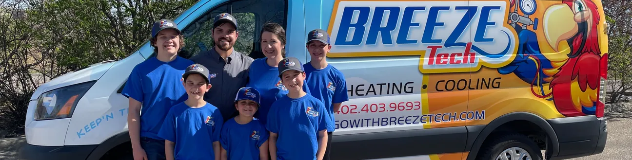 The BreezeTech Heating and Cooling family in matching blue shirts in front of the company van