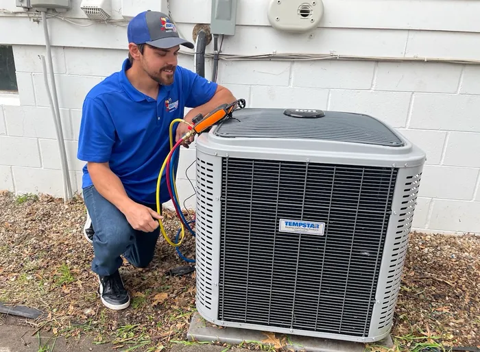 BreezeTech Heating and Cooling technician checking refrigerant pressures on a Tempstar air conditioner