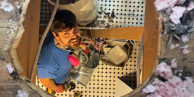 BreezeTech Heating and Cooling technician seen through a ceiling opening while running new ductwork