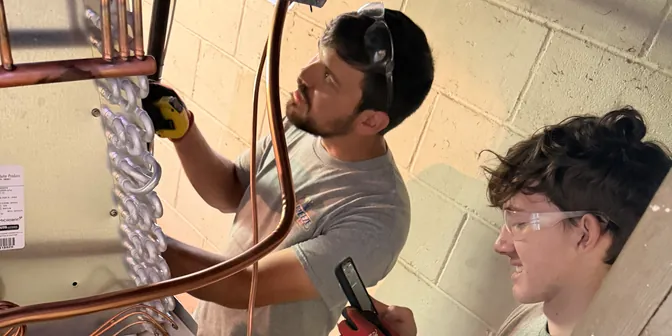 BreezeTech Heating and Cooling technicians brazing copper lines at a furnace and coil in a basement