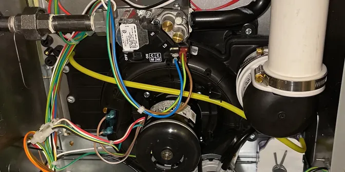 Inside a high-efficiency furnace showing the inducer motor and gas valve, serviced by BreezeTech Heating and Cooling