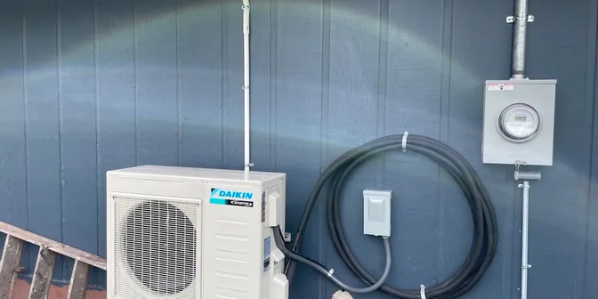 Daikin ductless mini-split outdoor unit mounted on a wall by BreezeTech Heating and Cooling