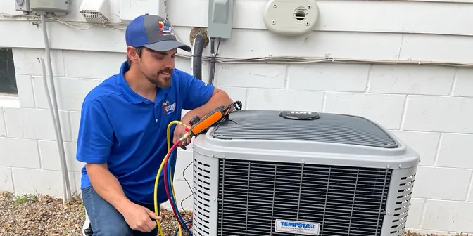 BreezeTech Heating and Cooling technician checking refrigerant pressures on a Tempstar air conditioner