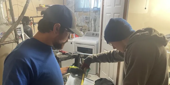 Two BreezeTech Heating and Cooling technicians measuring sheet metal for custom ductwork