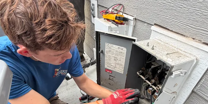 BreezeTech Heating and Cooling technician wiring an AC electrical disconnect