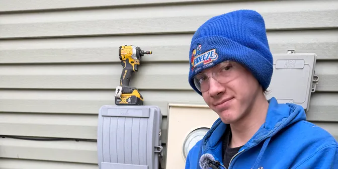 BreezeTech Heating and Cooling technician holding refrigerant manifold gauges next to a condenser
