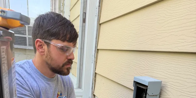 BreezeTech Heating and Cooling technician wiring a new AC disconnect box