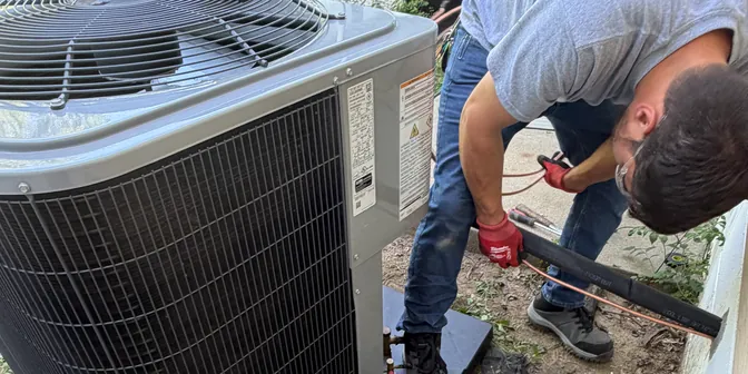 BreezeTech Heating and Cooling technician setting a new air conditioner on its pad