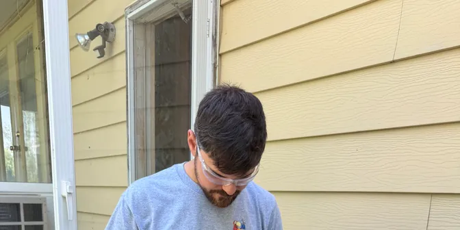 BreezeTech Heating and Cooling technician using a clamp meter on an air conditioner