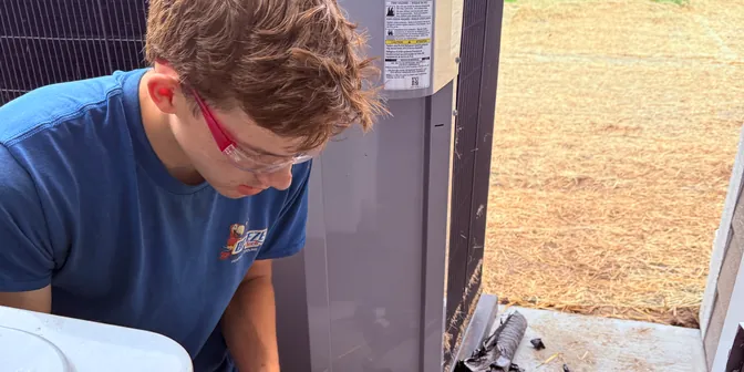 BreezeTech Heating and Cooling technician brazing refrigerant fittings at a commercial condensing unit