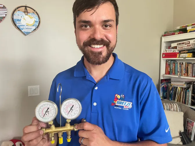 BreezeTech Heating and Cooling team member holding a set of refrigerant manifold gauges