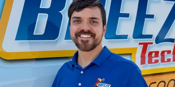 BreezeTech Heating and Cooling team member smiling in front of the company van