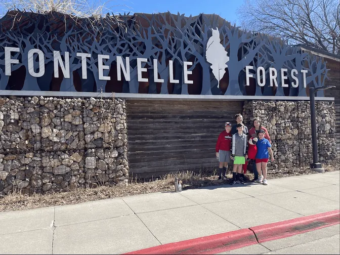 The family at the Fontenelle Forest entrance sign in Bellevue
