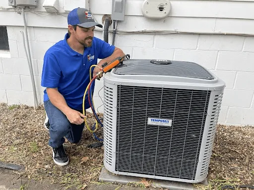 A BreezeTech technician checking an outdoor air conditioner