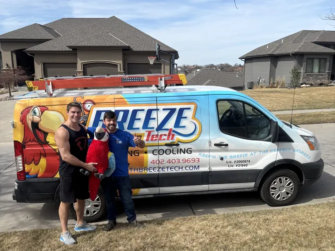 Micah and Heath with Max the Macaw beside the BreezeTech van