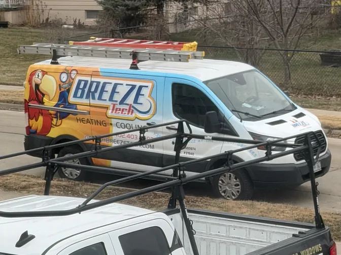 A BreezeTech service van beside a Pinnacle Roofing truck at an Omaha job site