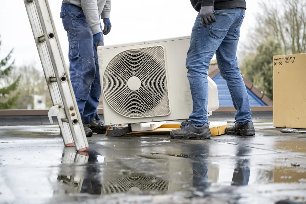 Two HVAC workers installing a new air conditioning unit.