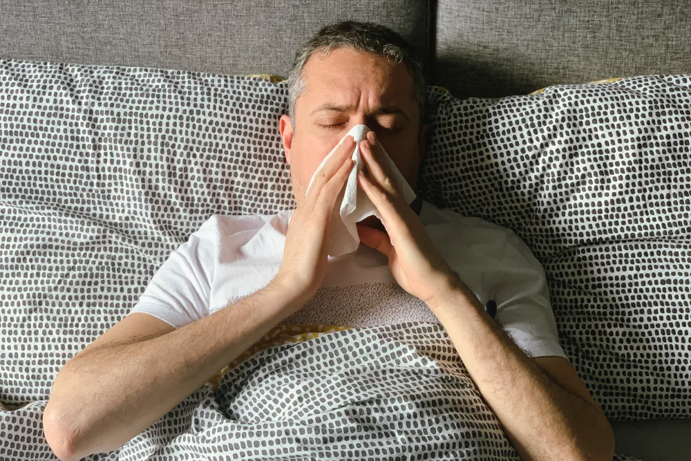 Man in bed suffering from allergies.